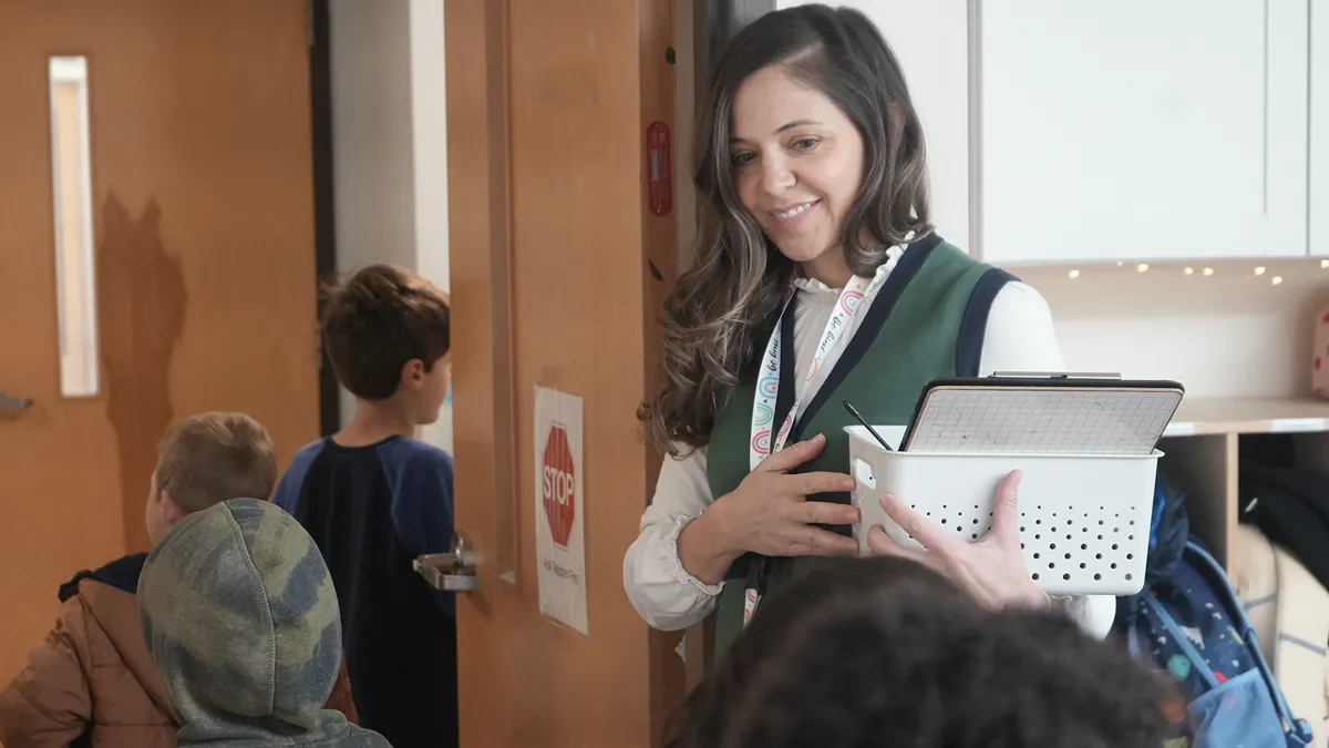 A Sterling Montessori teacher welcomes students at the classroom door